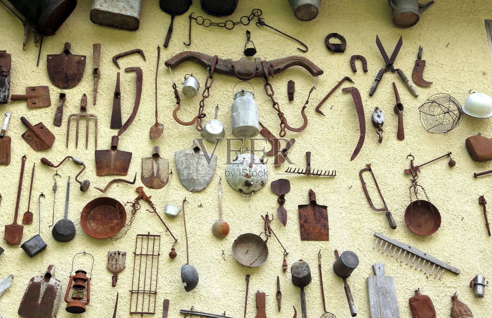 许多古老的农具挂在墙上照片摄影